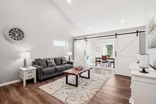 A living room with a grey couch, a coffee table, and a clock on the wall.