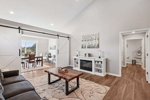 A modern living room with a black leather couch and a wooden coffee table.