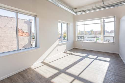 A sunny room with a large window and a wooden floor.