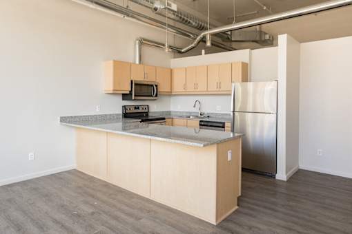 A kitchen with a refrigerator, microwave, and oven.