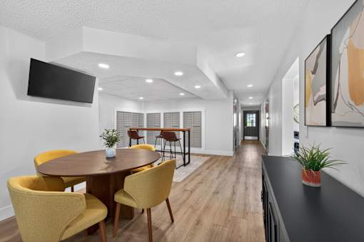 A modern dining room with a round table and yellow chairs.