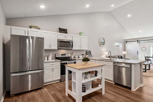 A kitchen with a wooden table and stainless steel appliances.