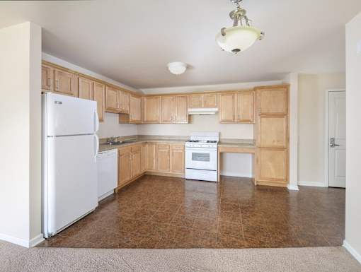 an empty kitchen with wood cabinets and white appliances
