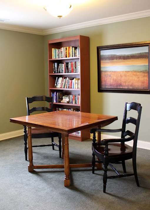 a table and chairs in a room with a book shelf