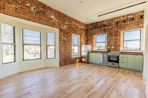 an empty living room with a brick wall and wood floors