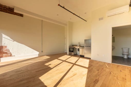 an empty living room with wood floors and a kitchen