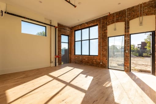 an empty living room with exposed brick and sliding glass doors