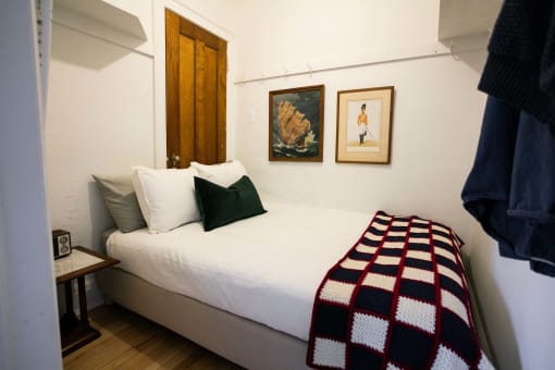 a bed in a small room with a blanket and pillows on it