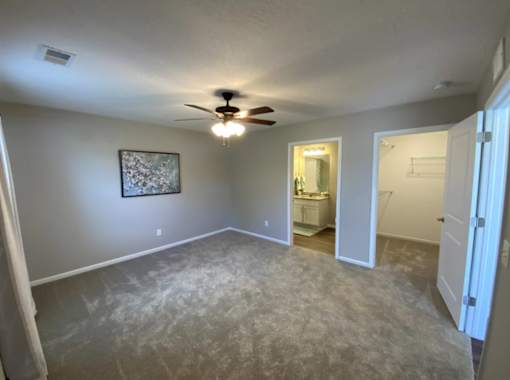 A room with a ceiling fan and a picture on the wall.