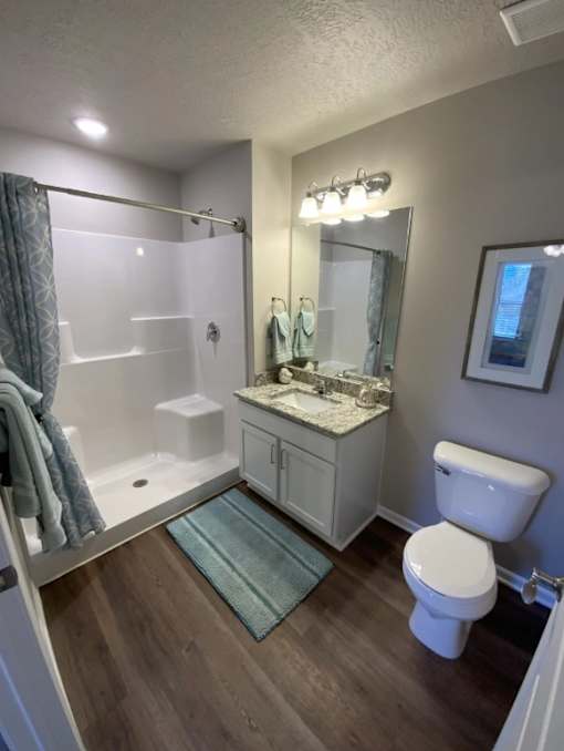 A bathroom with a white toilet, a sink with a mirror, and a bathtub with a shower curtain.