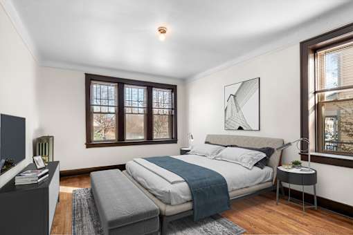 A bedroom with a bed, a nightstand, and a window.