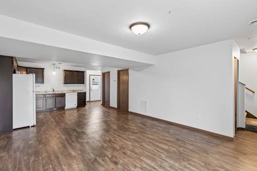 A kitchen with white appliances and wooden floors.