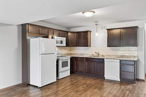 A kitchen with white appliances and brown cabinets.