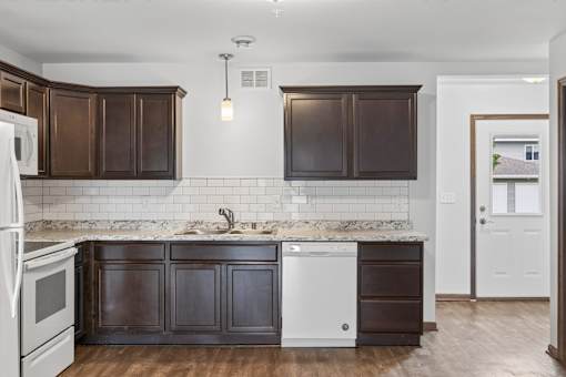 A kitchen with dark brown cabinets and a white fridge.