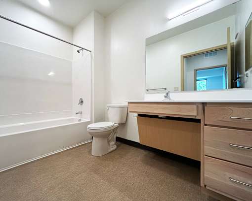 A white toilet sits in a bathroom next to a sink and a bathtub.