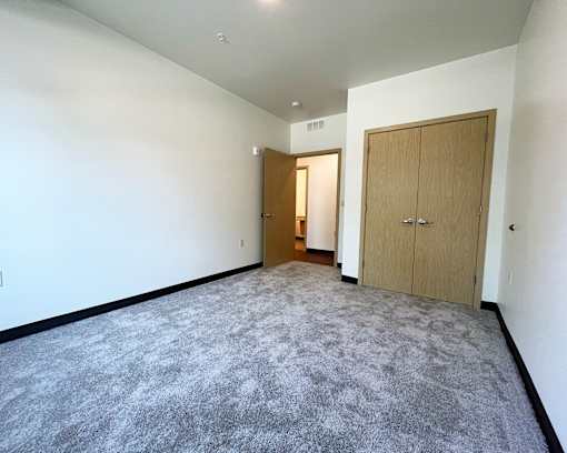 A room with a carpeted floor and two doors.