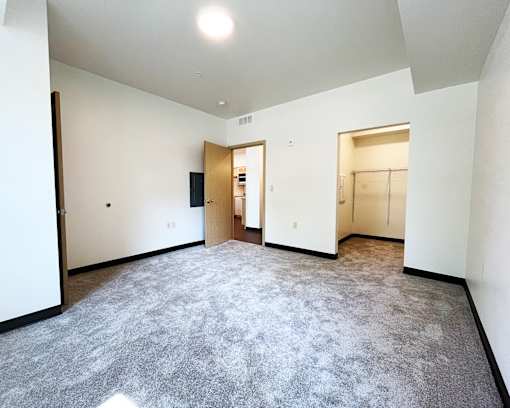 A large empty room with carpeted floor and white walls.