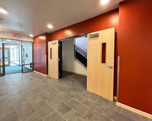 A hallway with a staircase and a red wall.