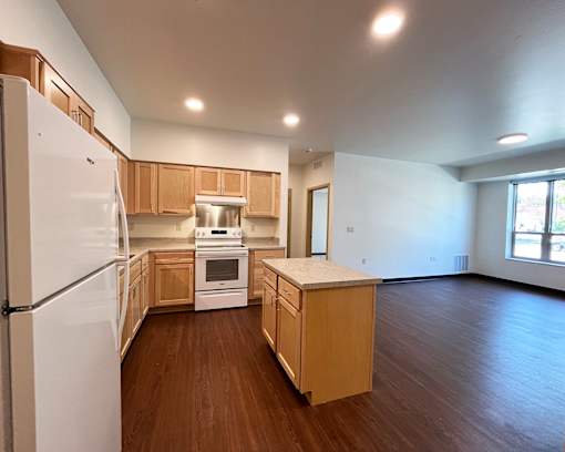 A kitchen with wooden floors and white appliances.