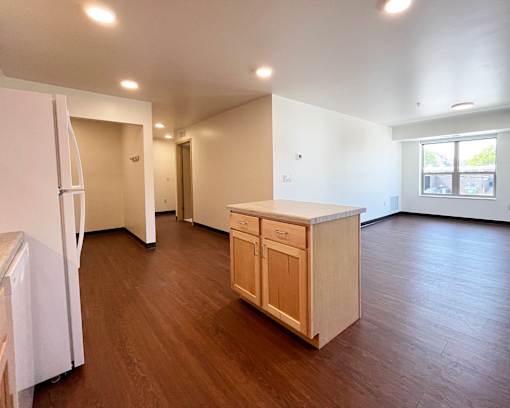 A kitchen with white appliances and wooden floors.
