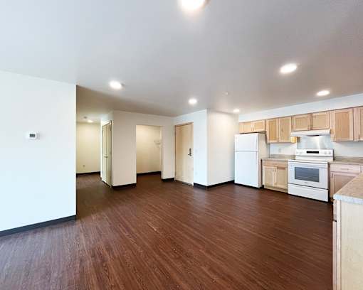 A kitchen with white appliances and wooden floors.