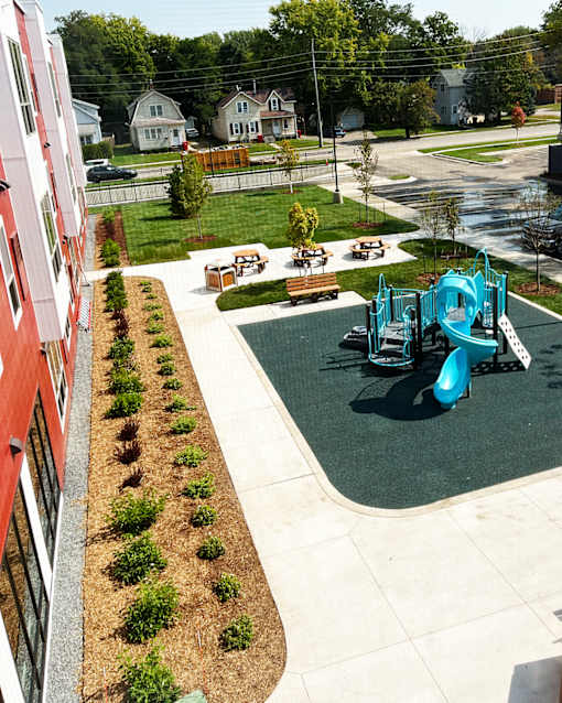 A playground with a blue slide and a red building on the left.