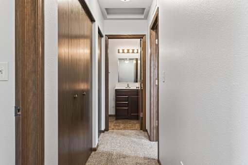 A hallway with a wooden door and a carpet on the floor.