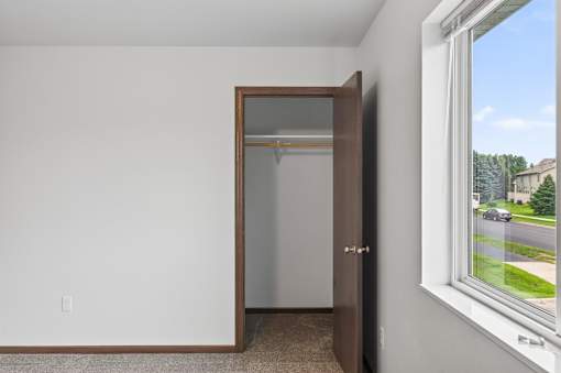 A room with a brown door and a window showing a street view.