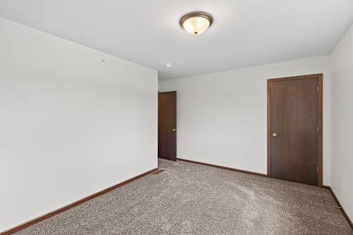 A room with two doors and carpeted floor.