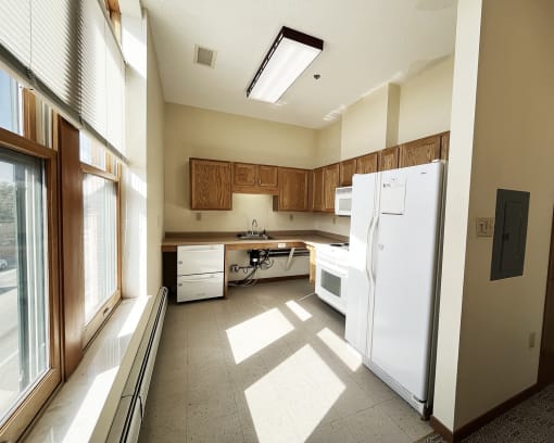 an empty kitchen with white appliances and wooden cabinets