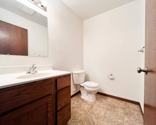 A white toilet sits in a bathroom next to a sink.