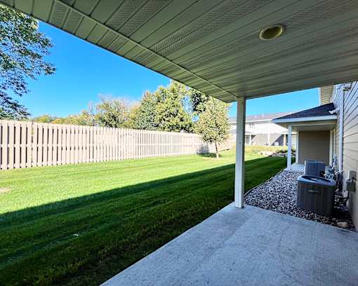 A backyard with a wooden fence and a covered patio area.