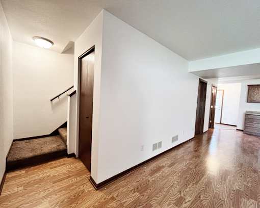 A hallway with a brown floor and white walls.