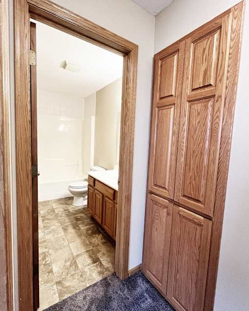 A bathroom with a toilet, sink and wooden door.