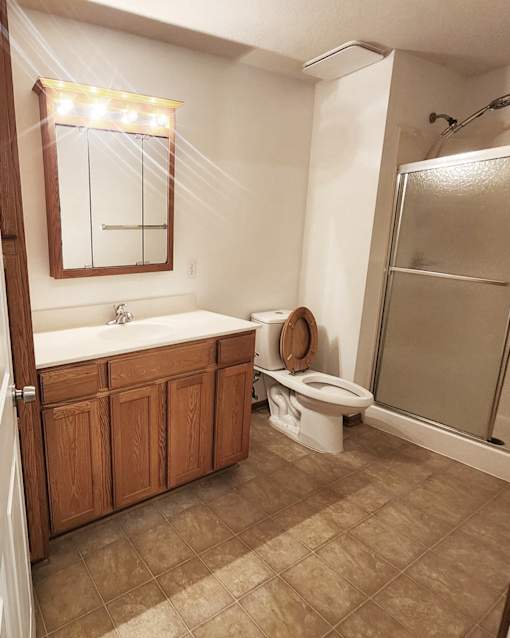 A bathroom with a toilet, sink, and mirror.