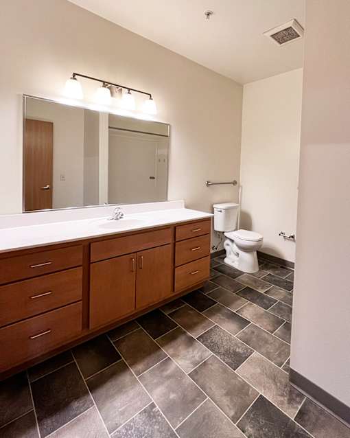 A bathroom with a white counter top and a white toilet.