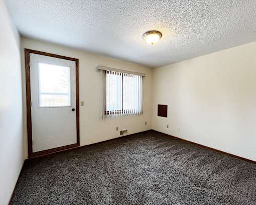 A room with a door, window, and carpeted floor.