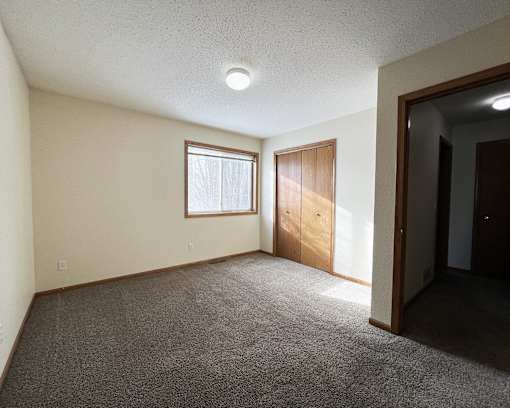 an empty living room with carpet and a door to a bedroom