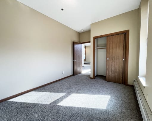 an empty living room with carpet and a door to a bathroom