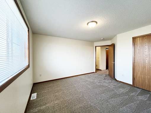 an empty living room with a large window and a door to a hallway