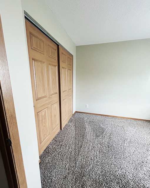 A room with a carpeted floor and a wooden door.