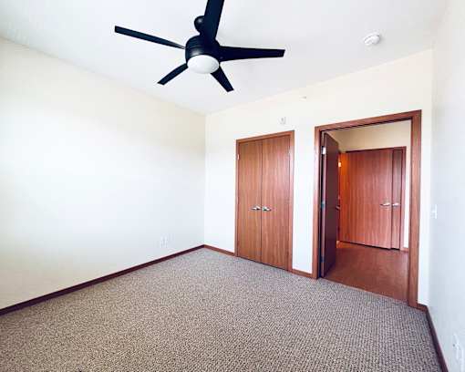 A room with a ceiling fan and carpeted floor.
