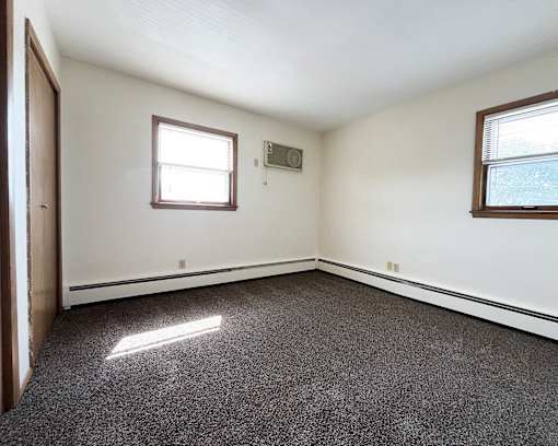 an empty room with a door and two windows