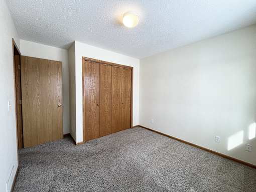 an empty room with carpet and a door to a closet
