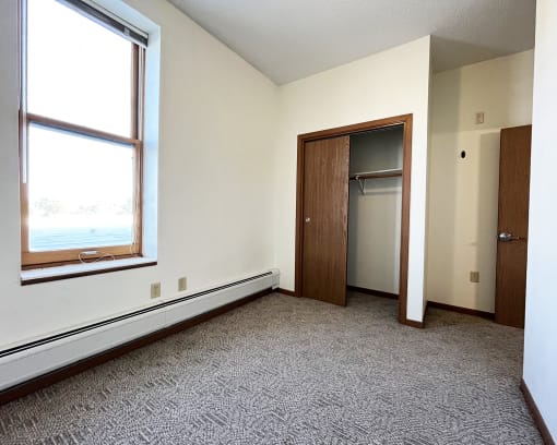 an empty room with a window and a closet