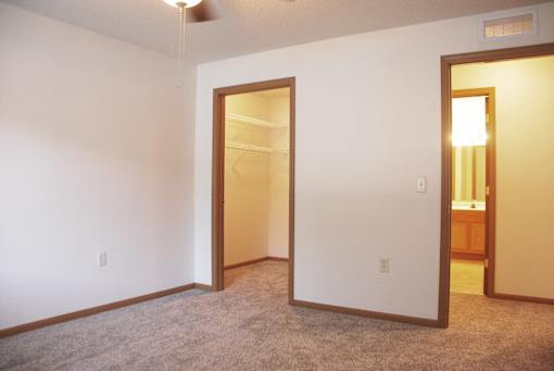 A room with a carpeted floor and two open doors.