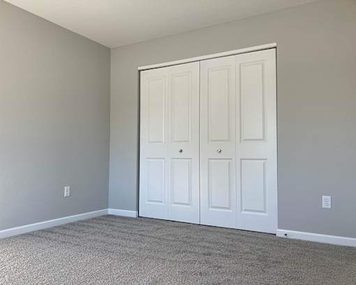 A room with a white door and carpeted floor.