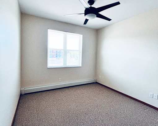 A room with a ceiling fan and a window.