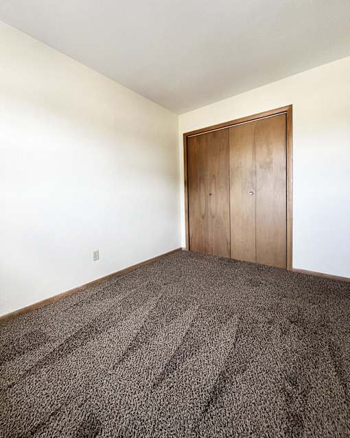an empty room with carpet and a wooden door