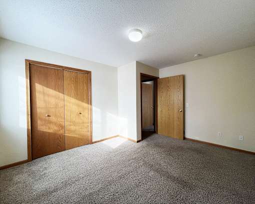 an empty living room with a door to a hallway and a closet